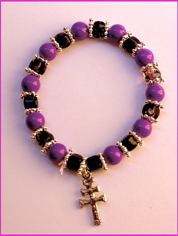 PULSERA CRUZ DE CARAVACA ELASTICA CON CORONITAS DORADAS MORADO Y NEGRO 